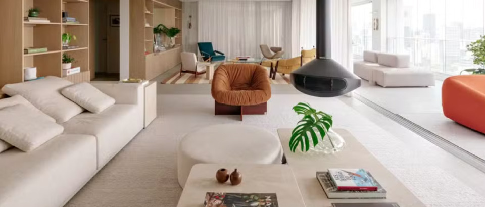 CASA E JARDIM | Apartamento tem sala de estar com mix de poltronas coloridas e lareira suspensa